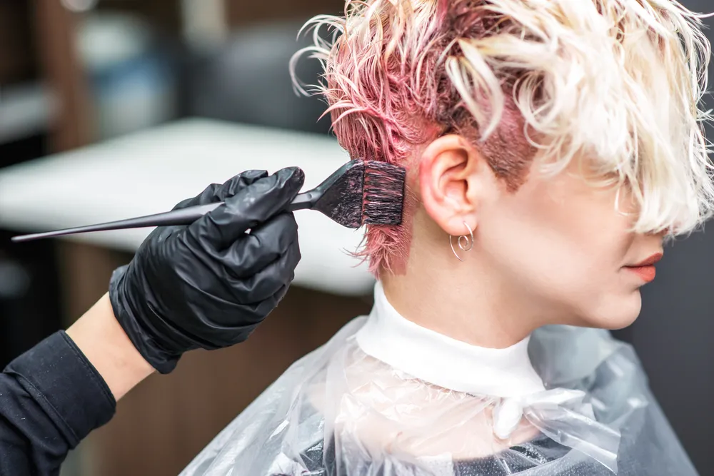A stylist applying color to a client’s hair in the salon