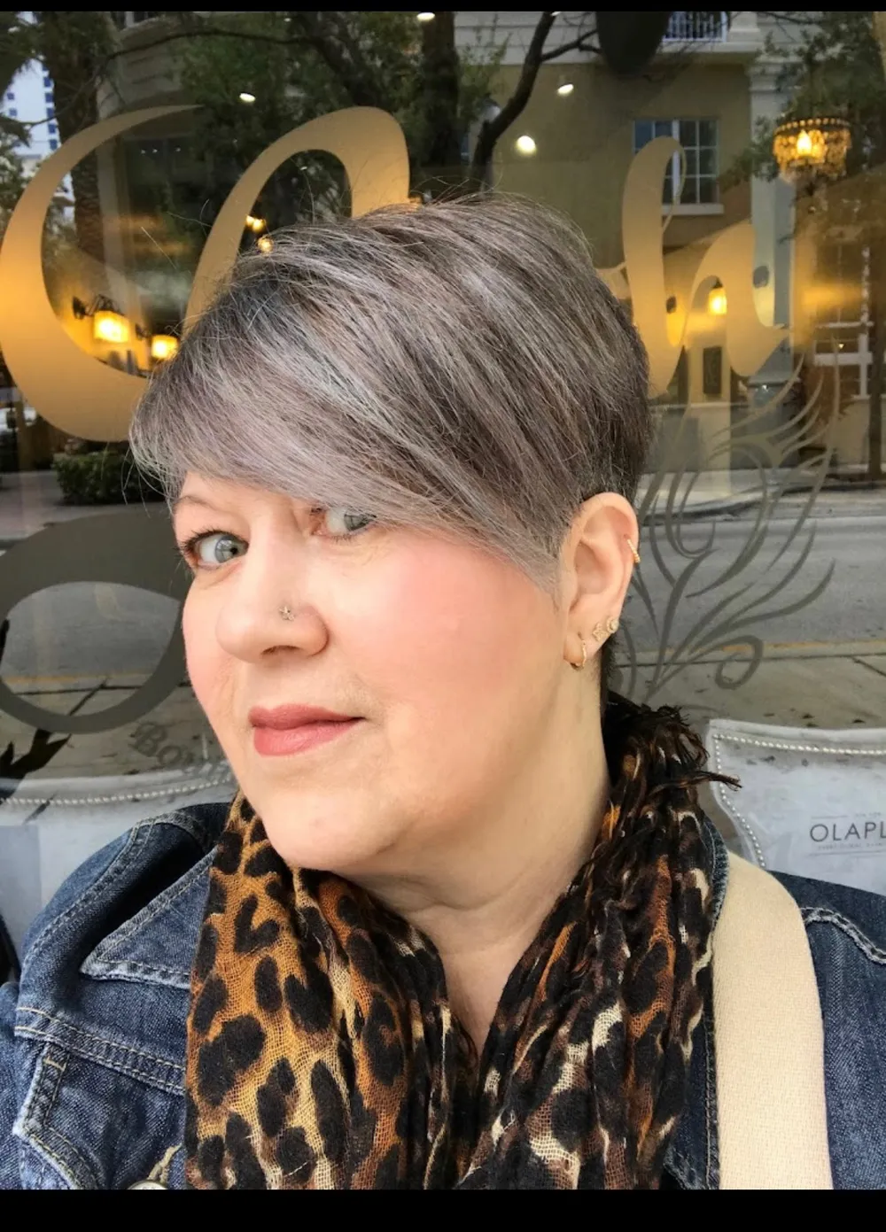 A client with a silver pixie cut, smiling in the salon