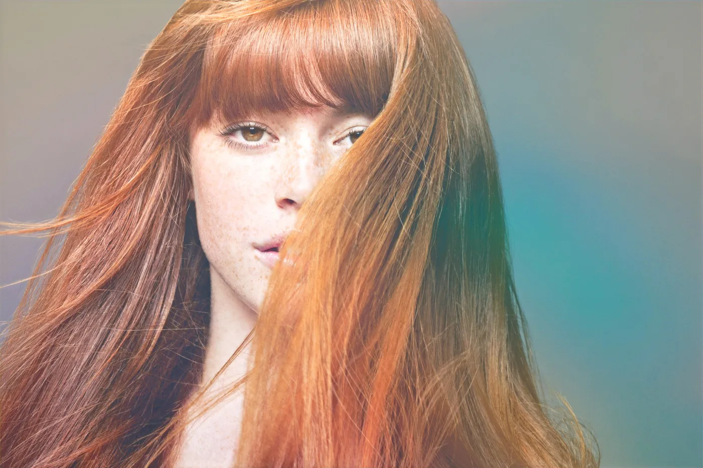 A client with long copper-red hair, photographed against a teal backdrop